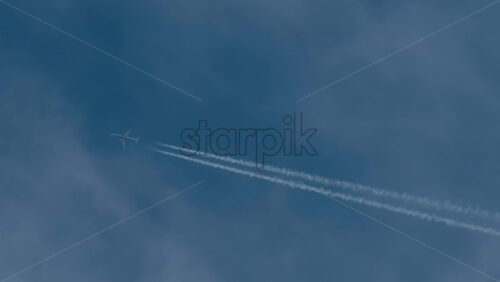 Video - Airplane flying high above leaving long contrails in a clear blue sky