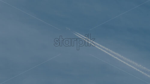 Video - Airplane flying high above leaving long contrails in a clear blue sky
