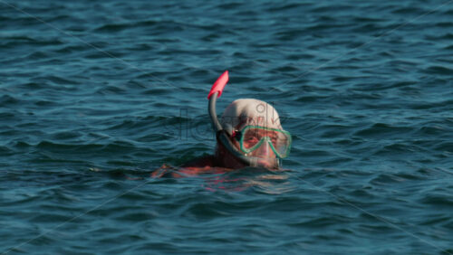 Video - Cannes, France - October 8, 2025: An elderly man swims with a snorkel and mask in the clear blue sea, exploring underwater life near the surface