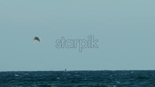 Video - View of a lone kitesurfer riding over the waves under the golden evening light
