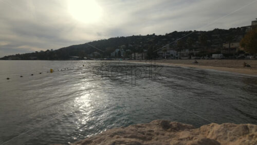 Video - Time lapse of a peaceful seaside view at sunset with gentle waves reflecting golden light and a coastal town in the background