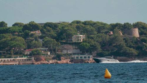 Video - A motor yacht cruises along the coast lined with beautiful villas surrounded by green pine trees