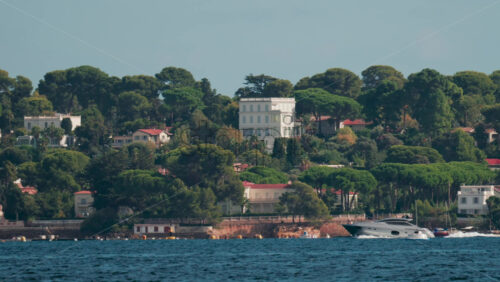 Video - A motor yacht cruises along the coast lined with beautiful villas surrounded by green pine trees
