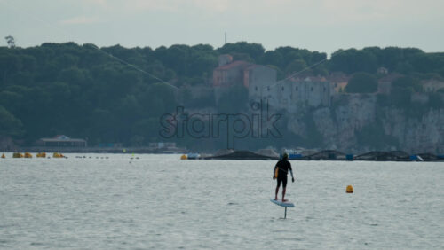 Video - Cannes, France - October 8, 2025: A man balances on an electric foilboard gliding smoothly over the water near the coast