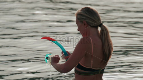 Video - Cannes, France - October 8, 2025: A woman standing in the water adjusts her snorkeling mask and tube under soft afternoon light