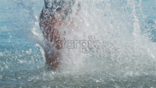 Video - Close up shot of legs splashing through seawater, with droplets frozen mid air