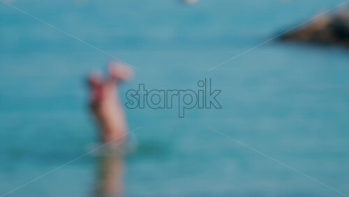 Video - Blurred view of a man swimming in the distance, against blue water