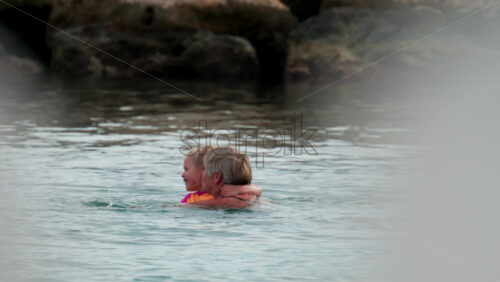 Video - Cannes, France - October 8, 2025: Tender moment of an elderly woman and young girl swimming together, smiling and embracing in calm seawater