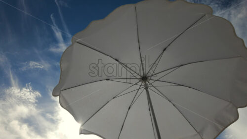 Video - Sunny seaside view with white beach umbrellas framing a bright blue sky and calm sea