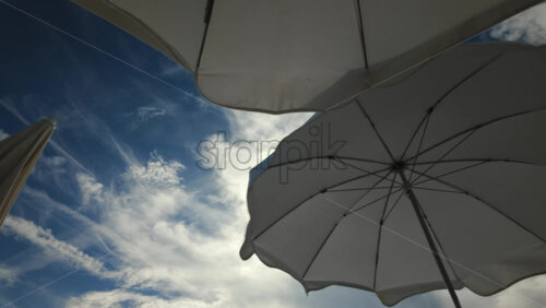 Video - Sunny seaside view with white beach umbrellas framing a bright blue sky and calm sea