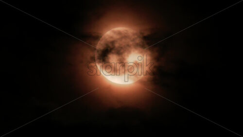 Video - Close up of a full moon glowing through dark clouds at night
