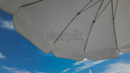 Video - Sunny seaside view with white beach umbrellas framing a bright blue sky and calm sea