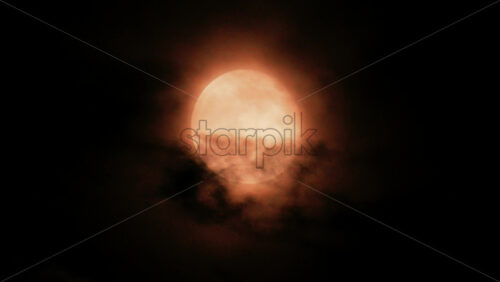 Video - Close up of a full moon glowing through dark clouds at night