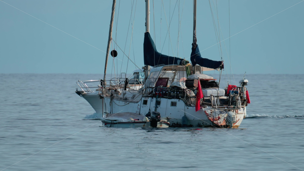 Video - Cannes, France - October 9, 2025: An old, weathered sailboat and a modern yacht floating side by side on tranquil waters