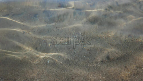 Video - Calm underwater view showing sand ripples and light reflections beneath the sea surface