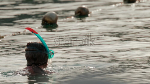 Video - Cannes, France - October 9, 2025: A woman prepares for snorkeling in the ocean, adjusting her mask while floating in gentle water under soft sunlight