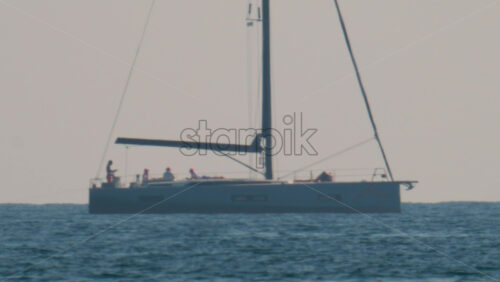 Video - A luxury sailboat with several people onboard cruising peacefully across the calm Mediterranean Sea