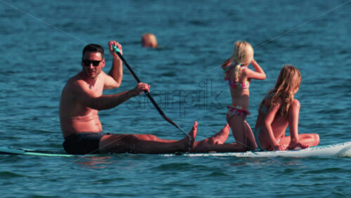 Video - Cannes, France - October 10, 2025: A man paddles on a stand-up board with two young girls enjoying a sunny day at sea