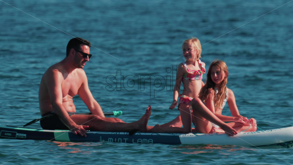 Video - Cannes, France - October 10, 2025: A man paddles on a stand-up board with two young girls enjoying a sunny day at sea