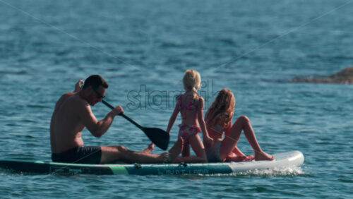 Video - Cannes, France - October 10, 2025: A man paddles on a stand-up board with two young girls enjoying a sunny day at sea