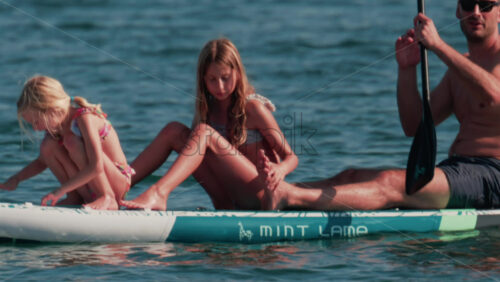 Video - Cannes, France - October 10, 2025: A man paddles on a stand-up board with two young girls enjoying a sunny day at sea