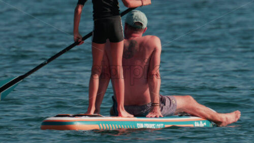 Video - Cannes, France - October 10, 2025: A man sits at the front of a paddleboard while a young child stands and rows at the back
