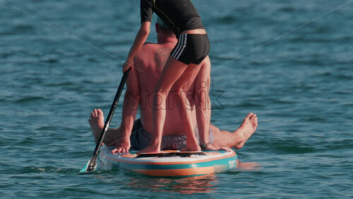 Video - Cannes, France - October 10, 2025: A man sits at the front of a paddleboard while a young child stands and rows at the back
