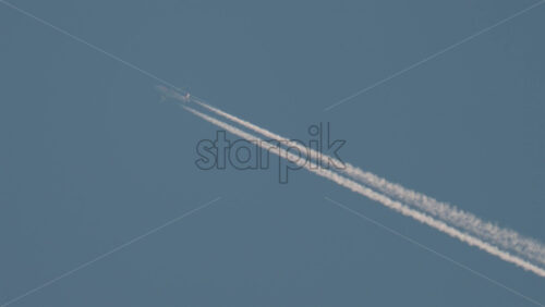 Video - Airplane flying high above leaving long contrails in a clear blue sky
