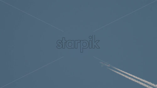 Video - Airplane flying high above leaving long contrails in a clear blue sky