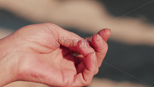 Video - Close up of a relaxed hand holding a cigarette in sunlight by the sea