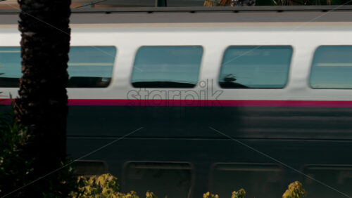 Video - Cannes, France - October 10, 2025: Close up of a high speed train creating a motion blur effect with reflections on its windows
