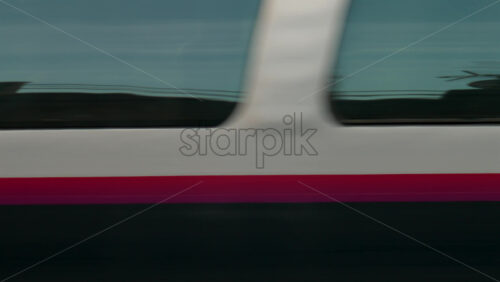 Video - Close up of a high speed train creating a motion blur effect with reflections on its windows
