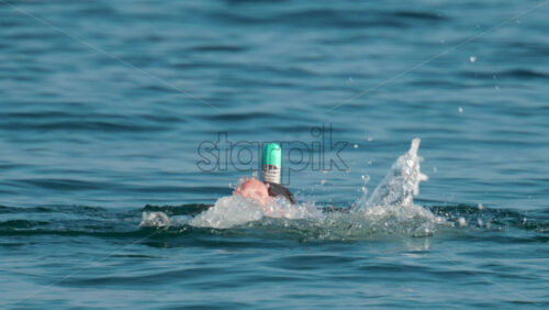 Video - A man wearing a full face snorkel mask floats calmly on the surface of the Mediterranean Sea