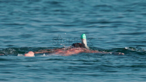 Video - A man wearing a full face snorkel mask floats calmly on the surface of the Mediterranean Sea