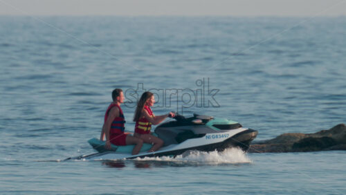 Video - Cannes, France - October 11, 2025: A couple wearing red and yellow life vests rides a jet ski together, smiling and enjoying the sea breeze