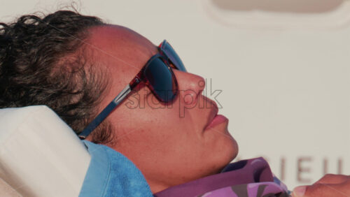 Video - Cannes, France - October 11, 2025: Close up of a woman wearing sunglasses and resting on a towel aboard a yacht