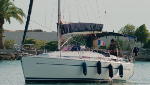 Video - Cannes, France - October 11, 2025: A white sailboat with two people onboard departs from the marina under a sunny sky