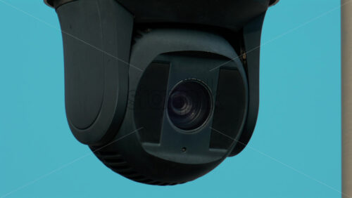 Video - A close up of a modern black surveillance camera turning against a bright sky background
