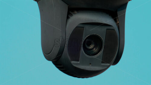 Video - A close up of a modern black surveillance camera turning against a bright sky background