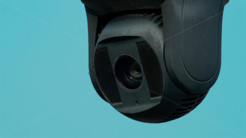 Video - A close up of a modern black surveillance camera turning against a bright sky background