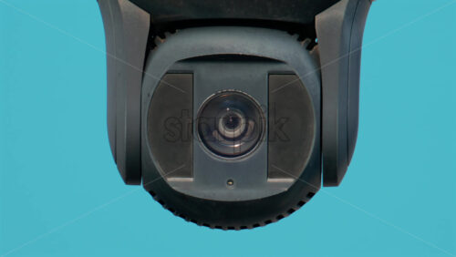 Video - A close up of a modern black surveillance camera turning against a bright sky background