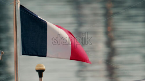 Video - The French flag flutters on a small boat mast with the reflection of the sea in the background