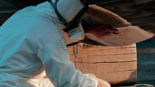 Video - Cannes, France - October 11, 2025: Two workers wearing protective white suits and respirators sand and repair the hull of a boat in dry dock