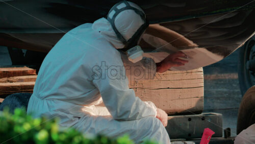 Video - Cannes, France - October 11, 2025: Two workers wearing protective white suits and respirators sand and repair the hull of a boat in dry dock