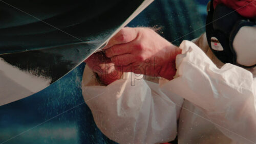 Video - Cannes, France - October 11, 2025: Two workers wearing protective white suits and respirators sand and repair the hull of a boat in dry dock