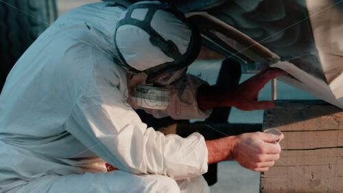 Video - Cannes, France - October 11, 2025: Two workers wearing protective white suits and respirators sand and repair the hull of a boat in dry dock