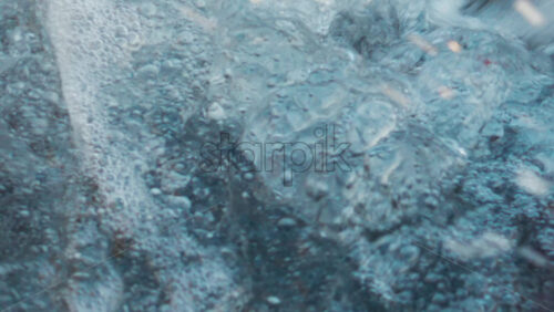 Video - Close up of seawater swirling between coastal rocks, forming white foam and bubbles