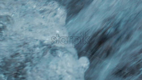 Video - Close up of seawater swirling between coastal rocks, forming white foam and bubbles