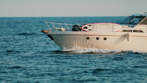 Video - A modern white yacht cruises smoothly across the blue sea under clear skies