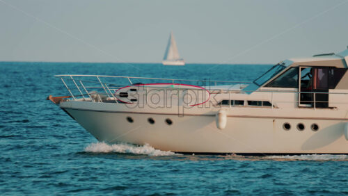 Video - A modern white yacht cruises smoothly across the blue sea under clear skies